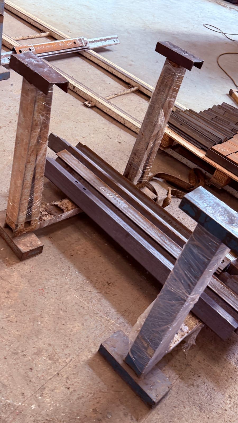 Bundled steel beam sections standing on a metal yard floor